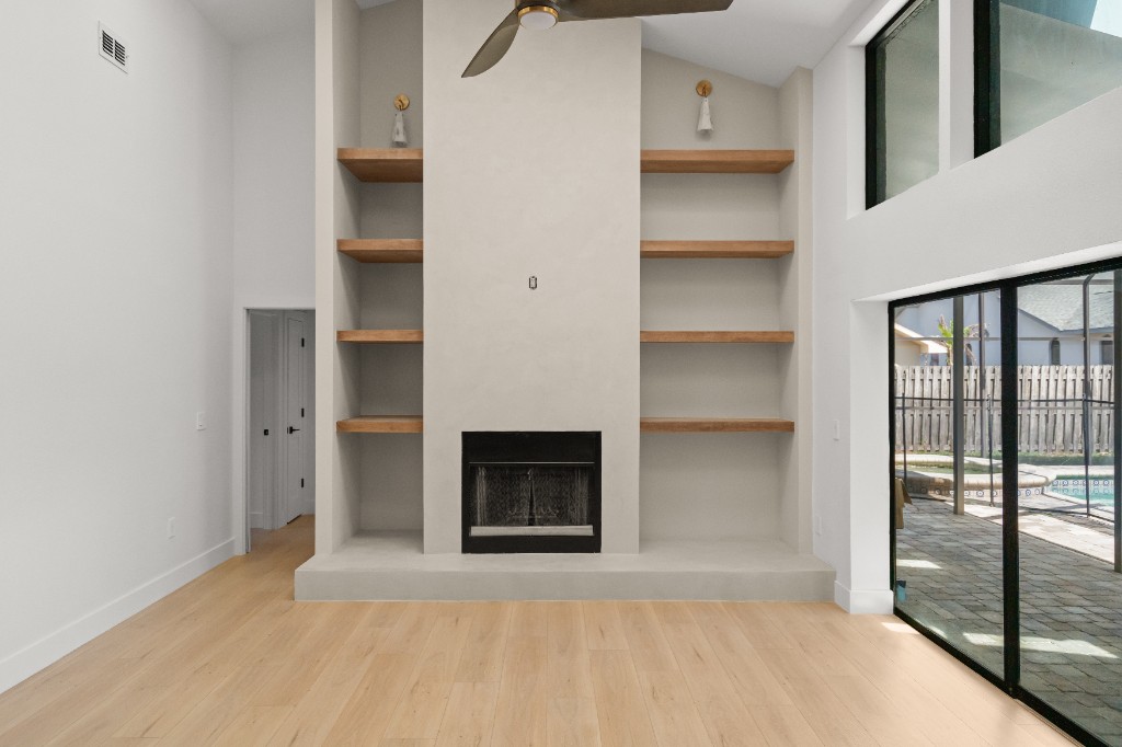 Renovated living room with fireplace, built-in shelving, and hardwood floors